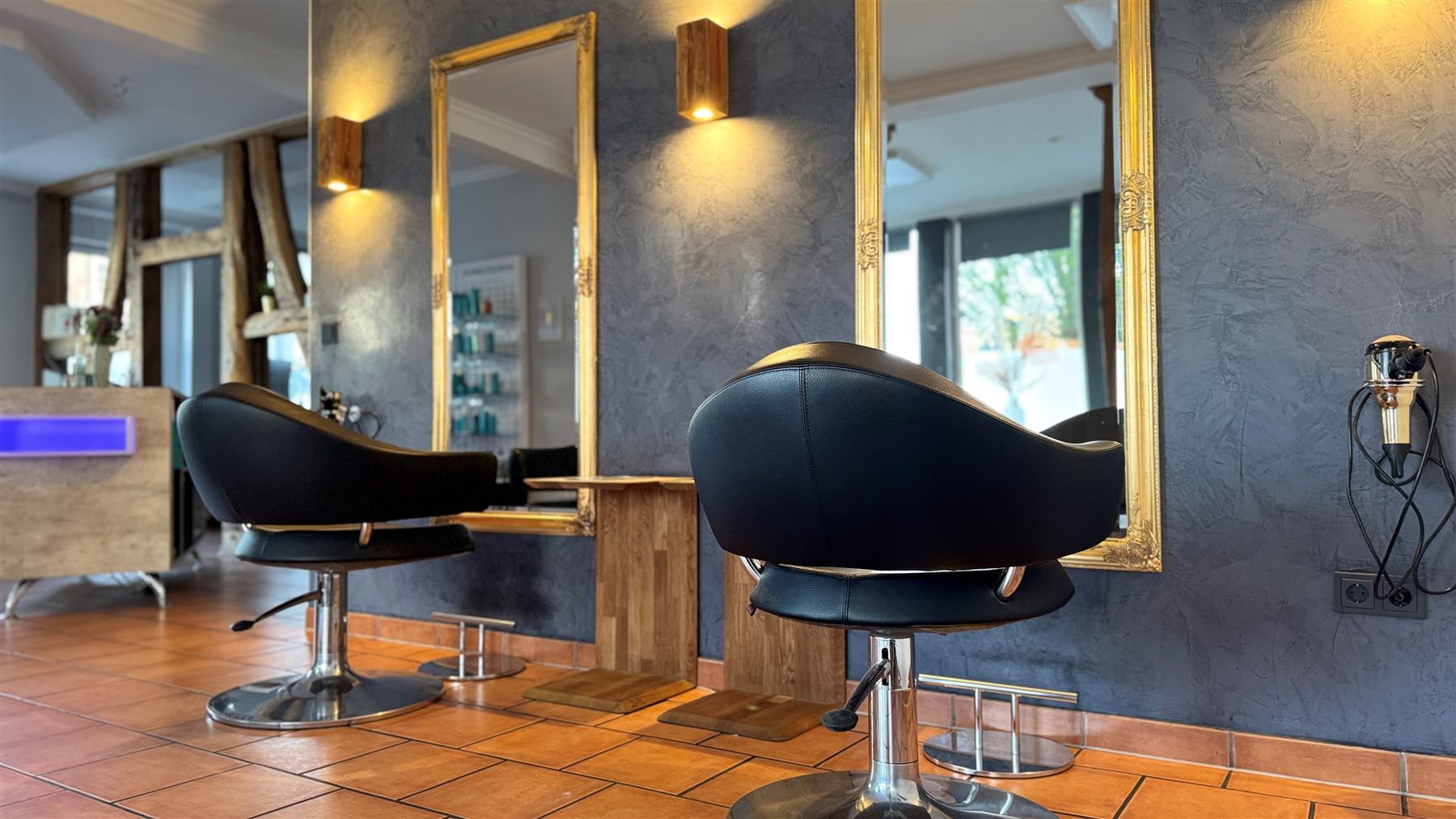 Innenraum von Salon Hairlich Südheide mit Empfang, Friseurplätzen und Pflegeprodukten